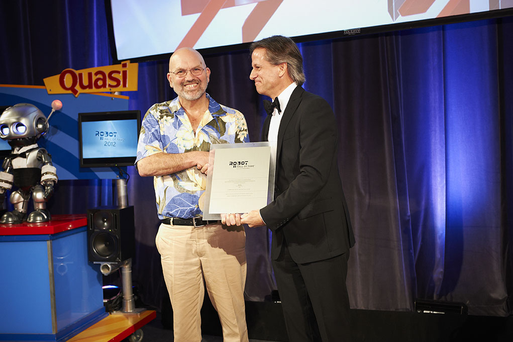 Marc Raibert, former CMU and MIT professor and the founder of Boston Dynamics, accepts a plaque from Henry Thorne, chief technology officer of 4Moms, signifying the 2012 induction of the four-legged BigDog. The Boston Dynamics robot entered the Robot Hall of Fame in the Research category.