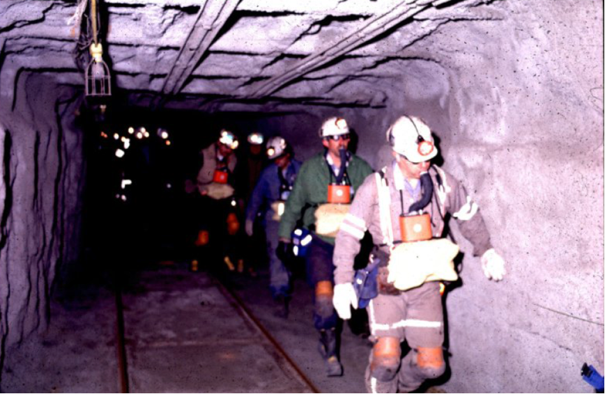 A group of adults, wearing specialized uniforms, walking in a dark tunnel