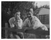 [de Mille and Kaye leaning on fence]