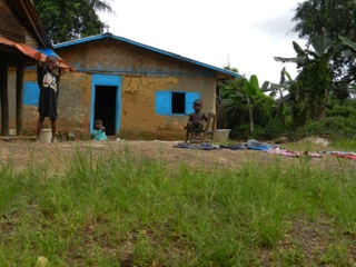 Children smiling in front of a small building under construction, Liberia