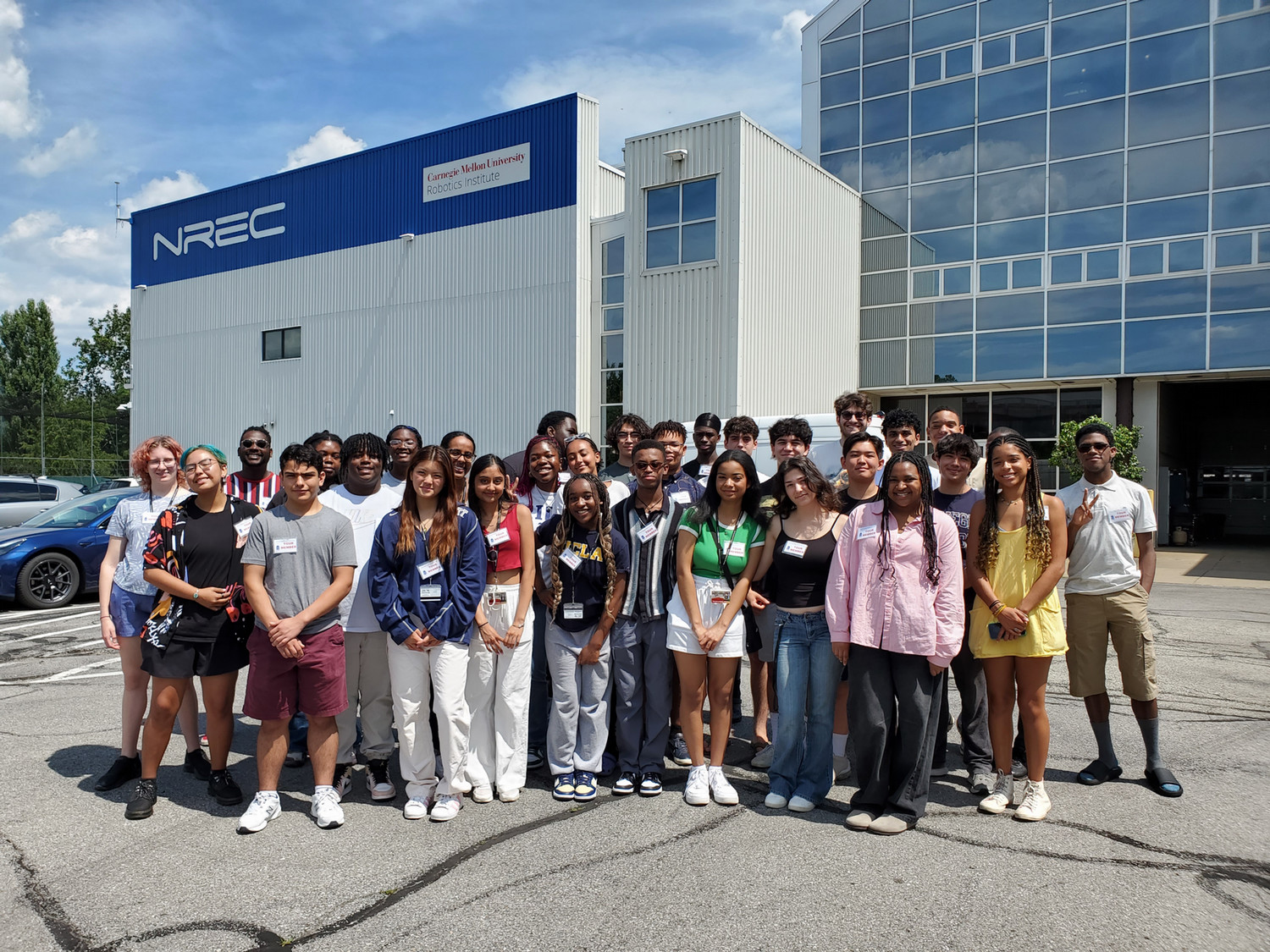 A large group of students standing in front of the exterior of CMU's National Robotics Engineering Center 