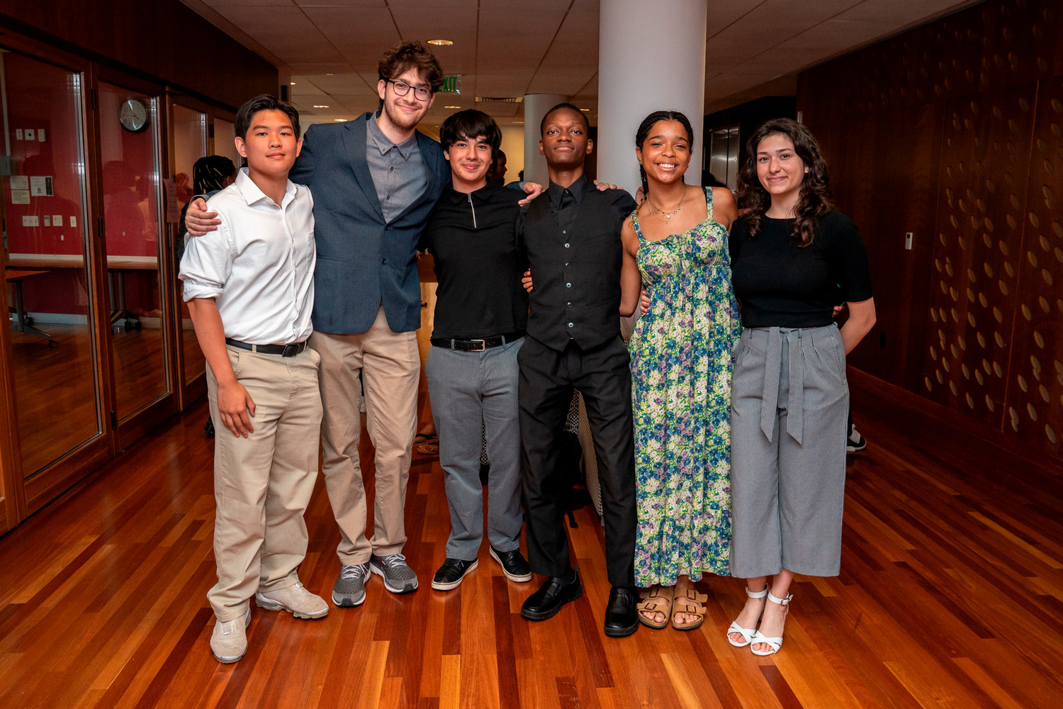 A group of four male students and two female students posing together in the hallway of the Gates Center.