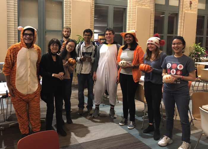 A group of students dressed in Halloween costumes holding pumpkins.