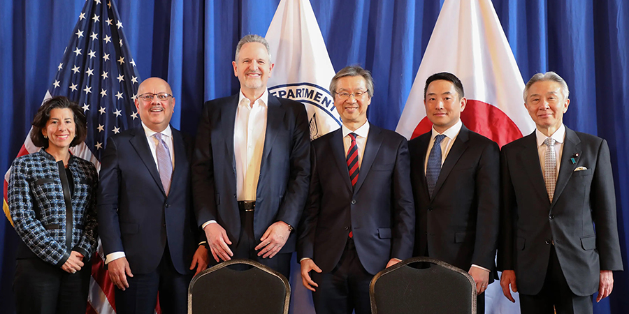  A group shot of the men and women who signed the agreement with the US and Japanese flags in the background.