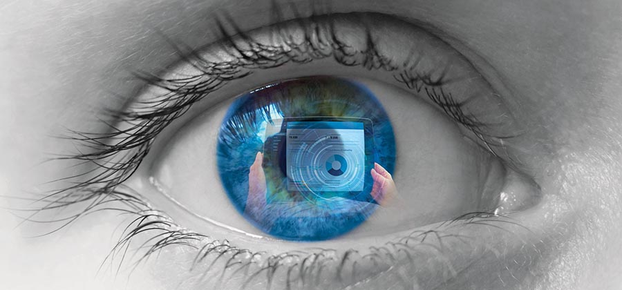 A person's hands holding a tablet device are reflecting in a human eyeball.