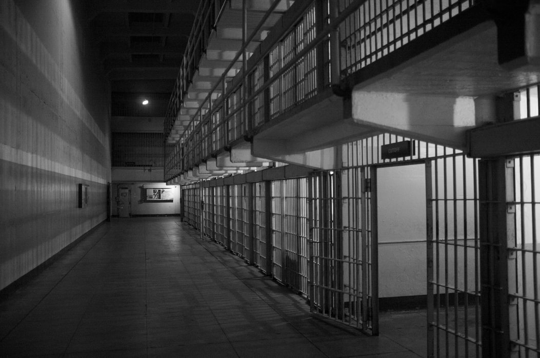 A black and white photograph of prison cells in dramatic lighting.