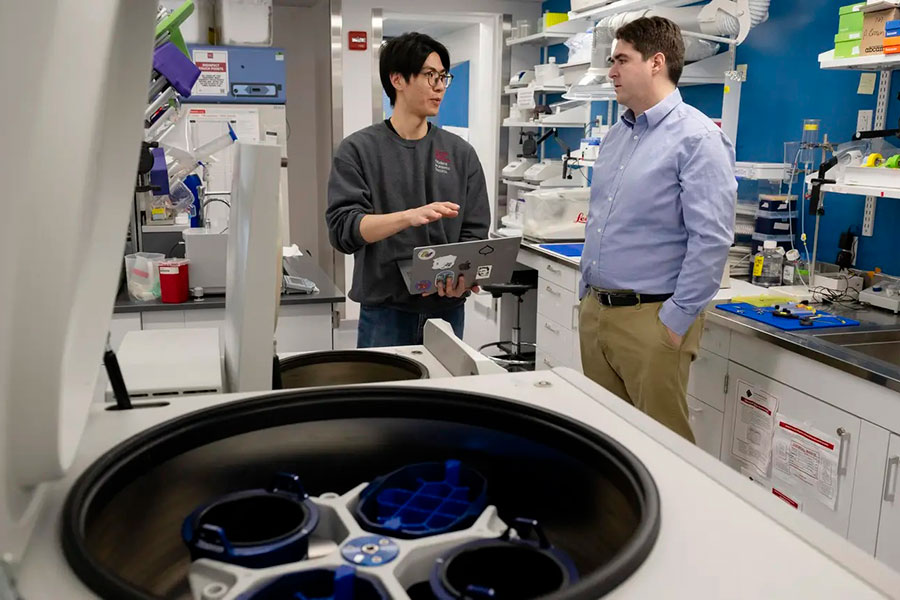  Two men stand in a laboratory, talking.