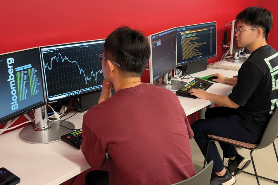  two students studying financial information on computer screens